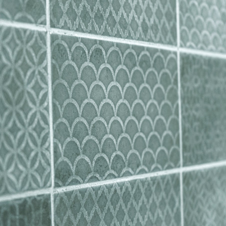 Green ceramic tiles display intricate, repeating patterns of arches and diamonds, creating a textured, decorative wall surface.