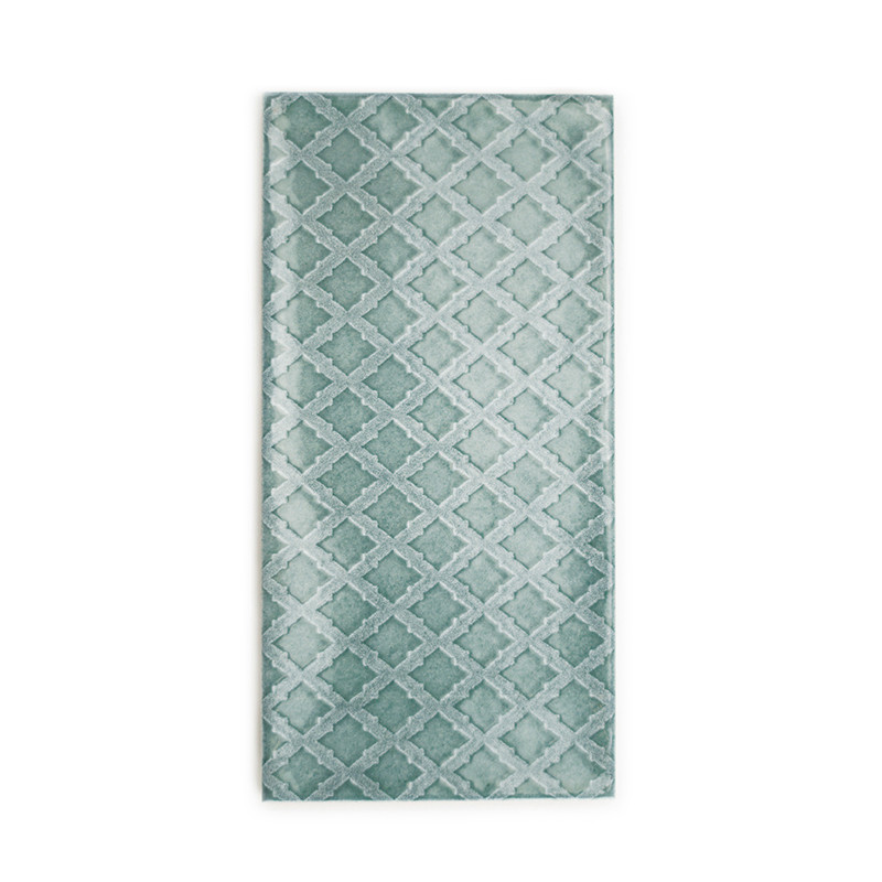 A rectangular tile displays a geometric pattern of interlocking diamonds in various shades of teal, set against a white backgrou