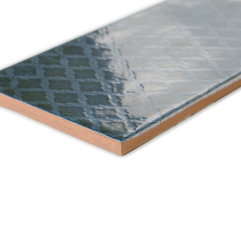 A rectangular ceramic tile features a glossy, dark blue surface with a subtle geometric pattern, placed on a plain white backgro