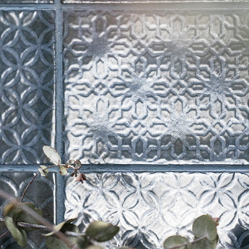 Les carreaux de verre décoratifs affichent des motifs géométriques complexes, réfléchissant la lumière. Un brin de petites feuil