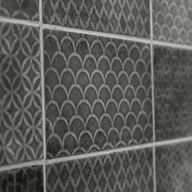 Eine Reihe strukturierter, dunkler Fliesen weisen geometrische Muster auf, darunter Schuppen und Gittermuster, die eine durchgeh