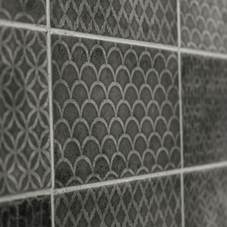 Uma série de azulejos escuros texturizados apresenta padrões geométricos, incluindo escalas e desenhos de treliça, formando uma  Uma série de azulejos escuros texturizados apresenta padrões geométricos, incluindo escalas e desenhos de treliça, formando uma