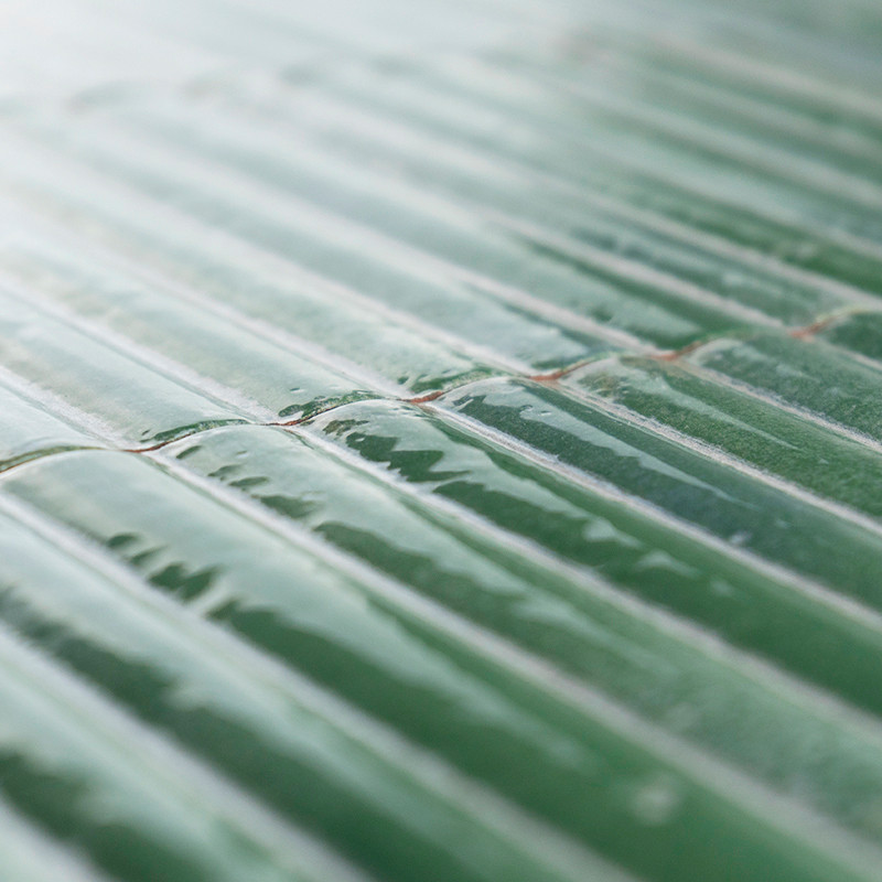 Groene keramische tegels op een rij gerangschikt, reflecterend licht en creëren een glanzend uiterlijk. Het oppervlak is enigszi