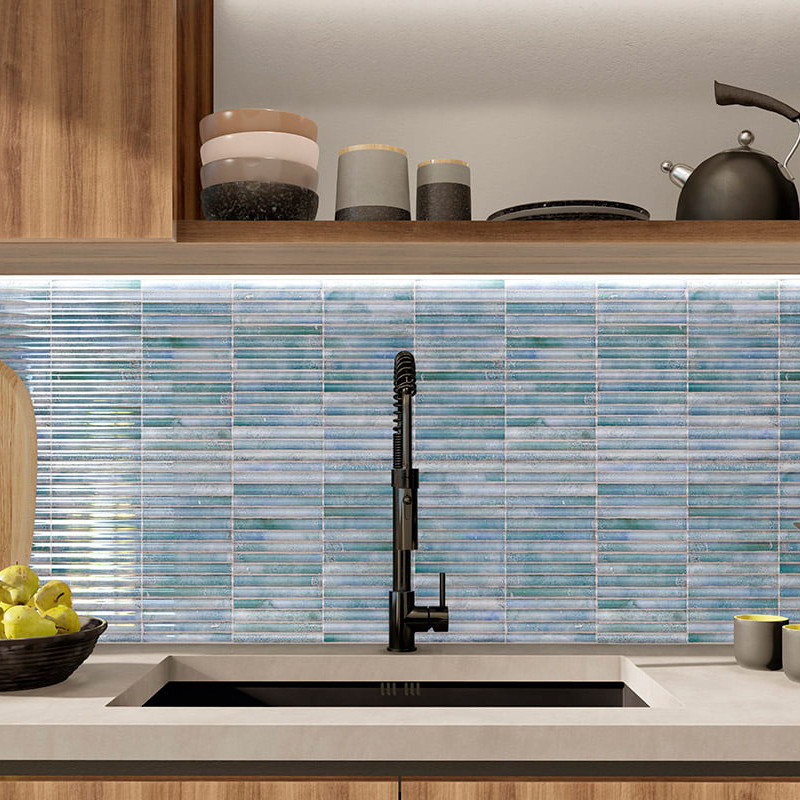 Mosaicos azuis revestem o backsplash da cozinha, complementando uma torneira preta sobre uma pia. armários de madeira e balcões 