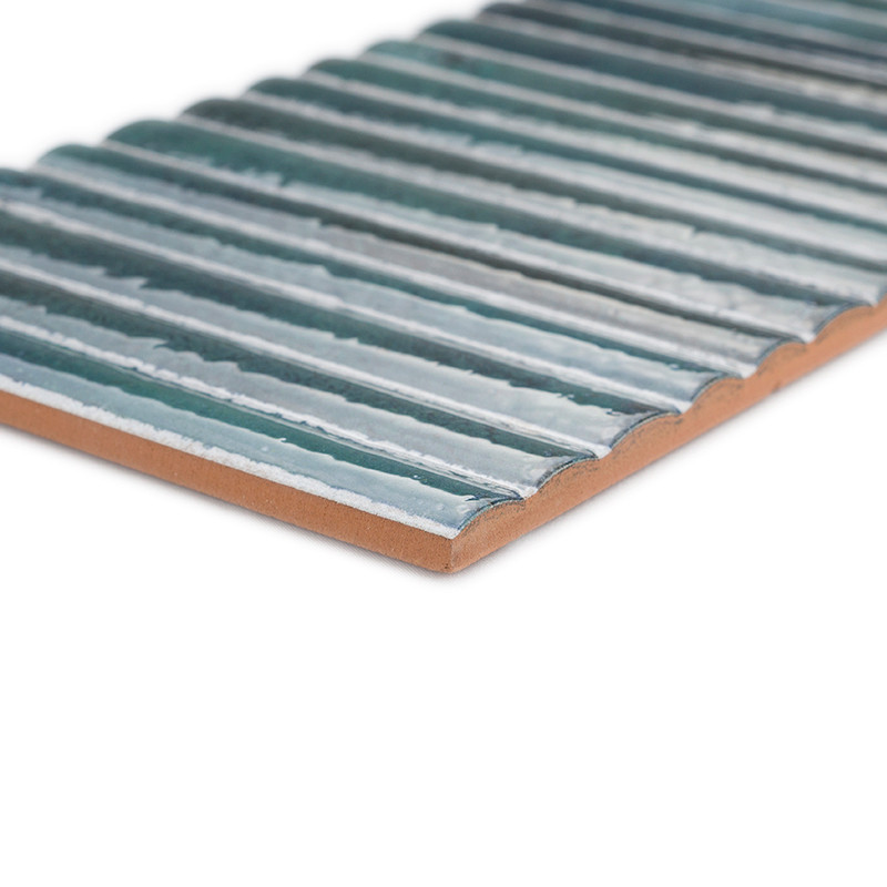 Um ladrilho cerâmico retangular apresenta cristas horizontais elevadas em um esmalte azul brilhante, contra uma borda lisa e pla