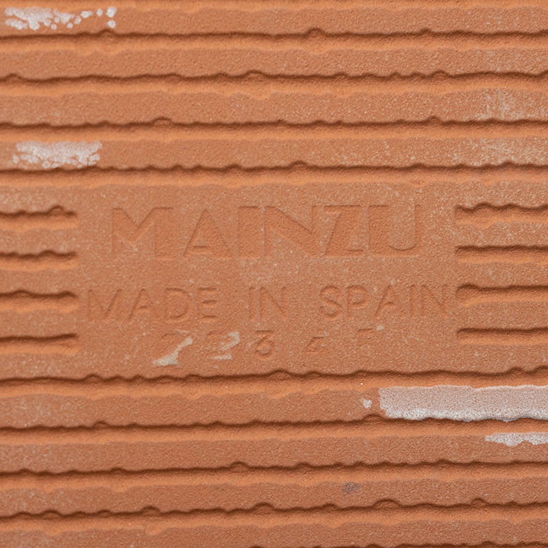 Auf der Terrakottafliese ist inmitten horizontaler Rillen der geprägte Text „MAINZU MADE IN SPAIN“ zu sehen, der auf Herkunft un