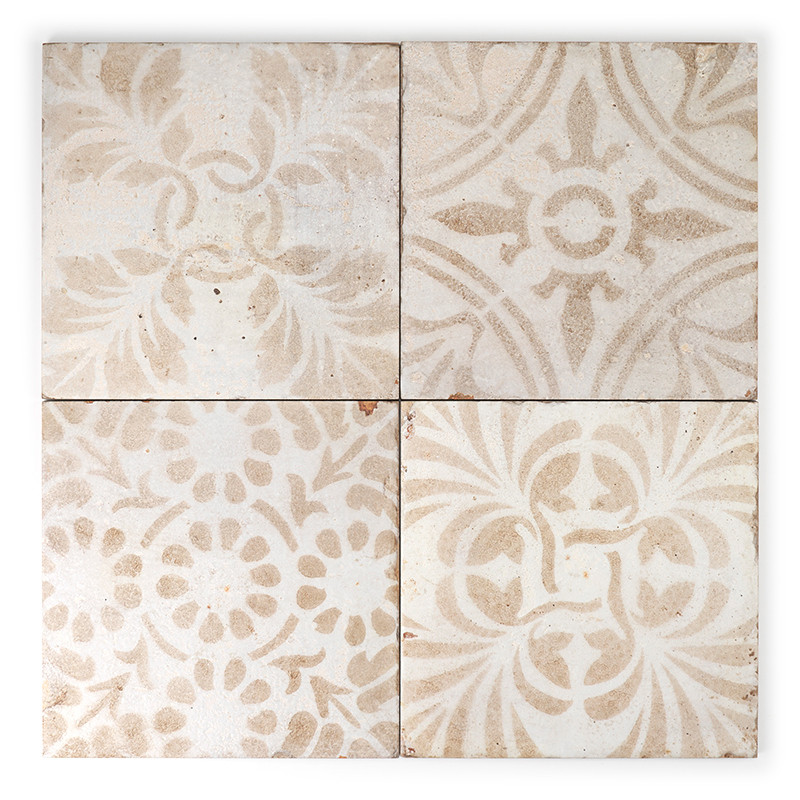 Vier beige und weiße Keramikfliesen weisen florale und geometrische Muster auf, die in einem Zwei-mal-Zwei-Raster auf einem einf