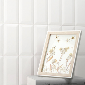 Ein mit Holzrahmen gerahmtes Bild zeigt Blumenkunst neben Sternmotiven und ruht auf zwei gestapelten Büchern vor einer geometris