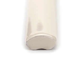 Um ladrilho cerâmico brilhante de cor creme fica horizontalmente, terminando em uma borda arredondada e lisa. É colocado sobre u