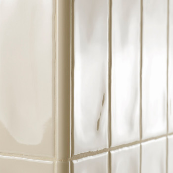 Glanzende beige tegels met gladde oppervlakken liggen in een hoek en reflecteren het licht, waardoor een strak, strak uiterlijk 