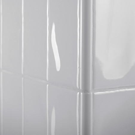 Glänzend weiße rechteckige Fliesen bedecken eine Eckwand und reflektieren das Licht in einem glatten, sauberen Gittermuster.