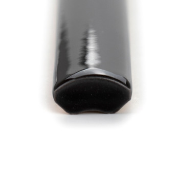 Eine glänzende, schwarze, viertelrunde Keramikfliese mit einer glatten, geschwungenen Kante ruht auf einem schlichten, weißen Hi