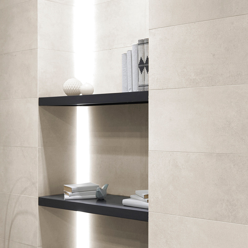azulejos de cerámica beige cubren una pared con estantes empotrados. Los objetos incluyen libros decorativos, jarrones y escultu