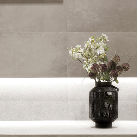 Un vase noir contient des fleurs blanches et violettes, posées sur un rebord en pierre claire contre un mur carrelé beige textur Un vase noir contient des fleurs blanches et violettes, posées sur un rebord en pierre claire contre un mur carrelé beige textur