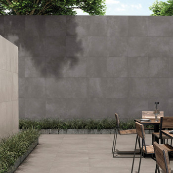 Um pátio minimalista de concreto apresenta cadeiras de madeira ao redor de uma mesa de metal, cercada por uma parede de azulejos
