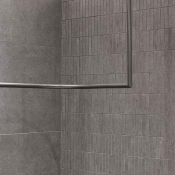 Graue rechteckige Fliesen säumen eine Wand- und Bodenecke und sorgen für einen modernen, minimalistischen Look. Ein Metallrahmen