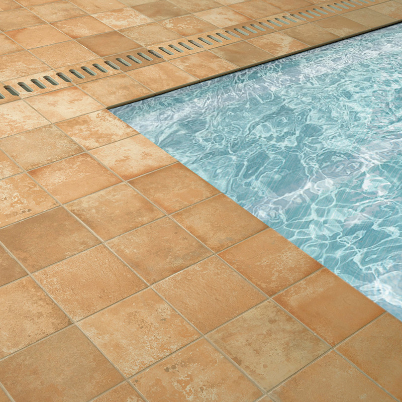 Terrakottafliesen umgeben einen funkelnden blauen Swimmingpool mit sichtbaren Wassermustern. Neben dem Beckenrand befindet sich 