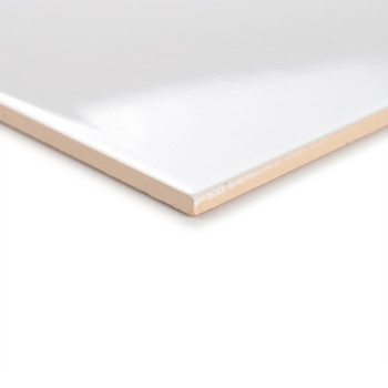 Een glanzende witte tegel ligt schuin en benadrukt het gladde oppervlak en de beige rand, tegen een neutrale achtergrond.