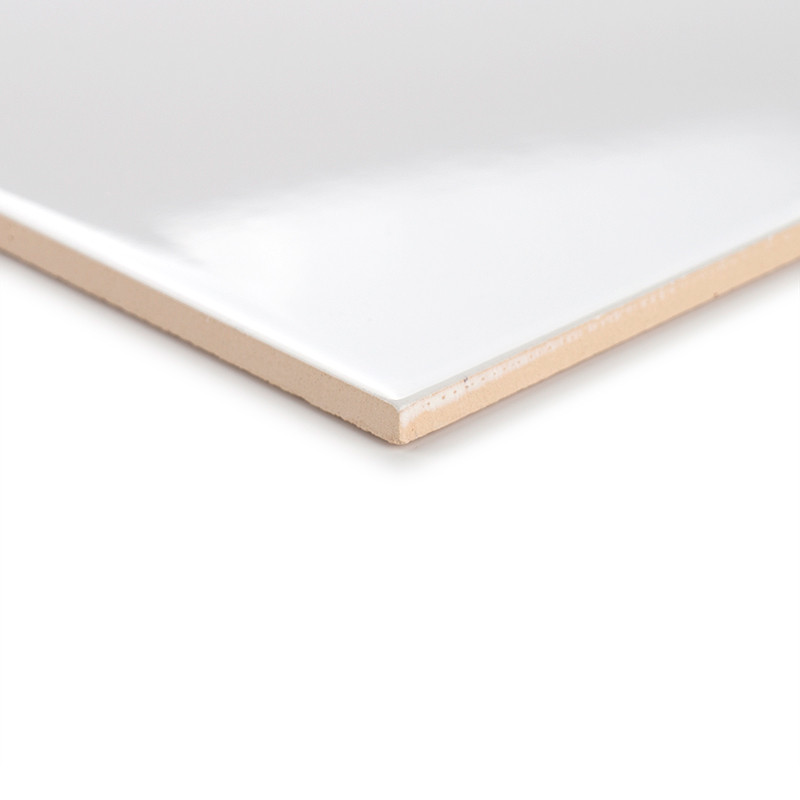 A glossy white tile rests at an angle, highlighting its smooth surface and beige edge, set against a neutral background.