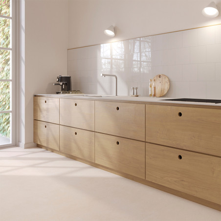 Eine moderne Küche verfügt über helle Holzschränke vor weiß gefliesten Wänden. Auf der Theke stehen eine Kaffeemaschine und ein 