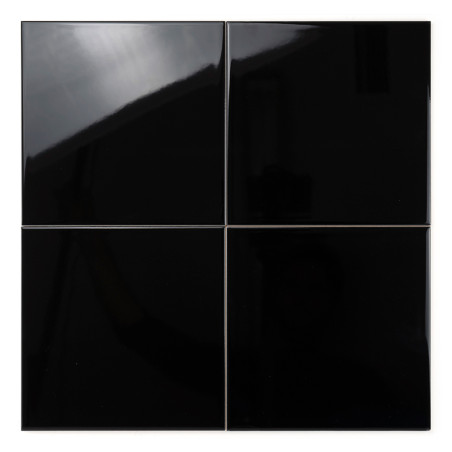 Quatro ladrilhos pretos brilhantes refletem a luz, dispostos em um padrão de grade quadrada, contra um fundo branco liso.
