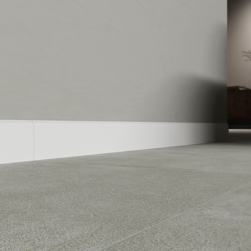 Un sol composé de plinthes grises lisses s'étend vers un mur discret avec des plinthes blanches, créant un espace intérieur épuré et moderne.