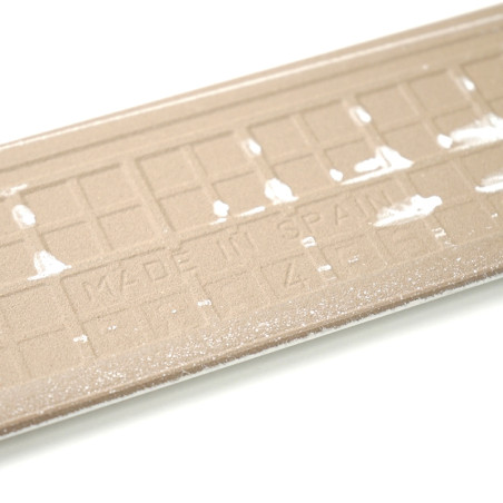 Textured beige rectangular skirting boards display the raised text 'MADE IN SPAIN' between faint white markings, set against a plain white background. Textured beige rectangular skirting boards display the raised text 'MADE IN SPAIN' between faint white markings, set against a plain white background.