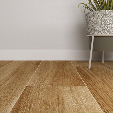 Carefully arranged wooden skirting boards, resembling natural oak boards. Next to them, a gray pot on legs holds a green plant, leaning against a plain white wall. Carefully arranged wooden skirting boards, resembling natural oak boards. Next to them, a gray pot on legs holds a green plant, leaning against a plain white wall.