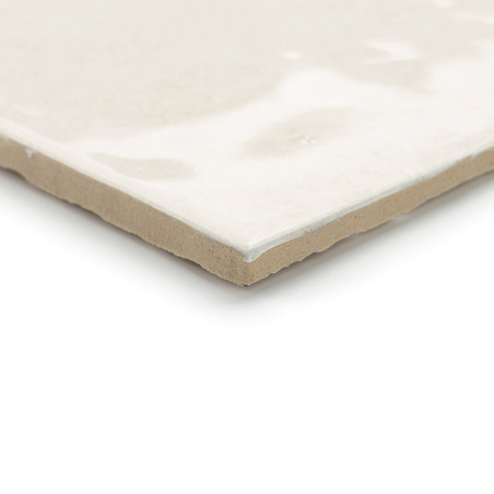 Eine Keramikfliese liegt flach auf einem weißen Hintergrund und weist eine glänzende, glatte, cremefarbene Oberfläche mit subtil