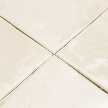 Cremefarbene Keramikfliesen, die in einem Gittermuster angeordnet sind, mit leichter Textur und sichtbaren Fugenlinien, wodurch 