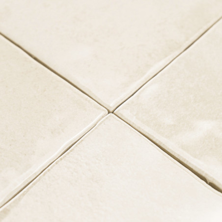 Cremefarbene Keramikfliesen, die in einem Gittermuster angeordnet sind, mit leichter Textur und sichtbaren Fugenlinien, wodurch 