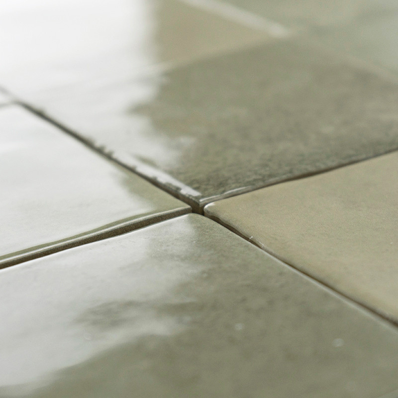 Les carreaux carrés verts brillants réfléchissent la lumière, créant une surface brillante et lisse. Ils sont disposés uniformém