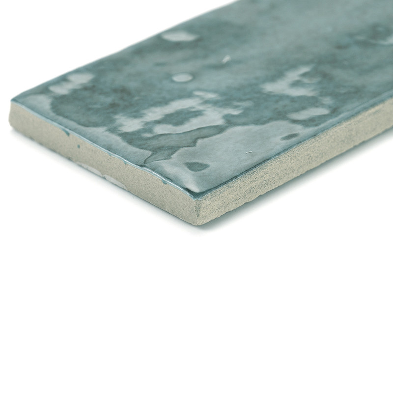 Rectangular ceramic tile with a glossy, mottled dark teal surface, lies flat against a white background, highlighting its textur