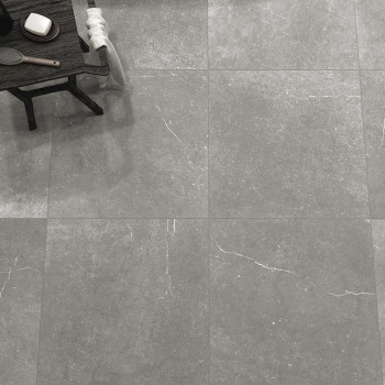 Grijze steentegels bedekken een vloer, met subtiele witte aderen. Aan de zijkant staat een houten tafel met verzorgingsspullen, 
