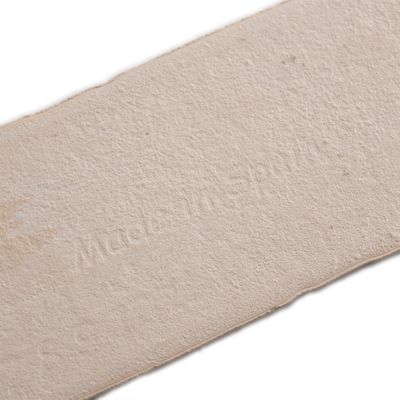 Azulejo retangular bege com superfície texturizada, exibindo o texto `Made in Spain`, sugerindo sua origem. posicionado sobre um
