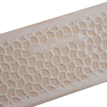 Beige rectangular tile displays geometric patterns with curved, interlocking shapes in raised relief. `MADE IN SPAIN` is embosse