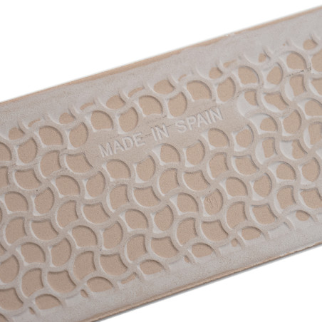 Beige rectangular tile displays geometric patterns with curved, interlocking shapes in raised relief. `MADE IN SPAIN` is embosse