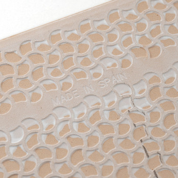 A tile displays a carved, repetitive leaf pattern with `MADE IN SPAIN` embossed, showcasing intricate design details on a light 
