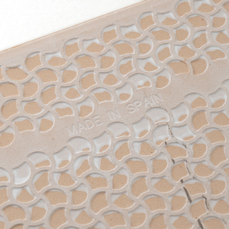 A tile displays a carved, repetitive leaf pattern with `MADE IN SPAIN` embossed, showcasing intricate design details on a light A tile displays a carved, repetitive leaf pattern with `MADE IN SPAIN` embossed, showcasing intricate design details on a light