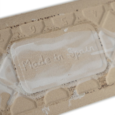 Auf einer beigen Fliese ist in einem rechteckigen Bereich der Text „Made in Spain“ eingeprägt. Die umliegenden Zahlen „9“ und „7 Auf einer beigen Fliese ist in einem rechteckigen Bereich der Text „Made in Spain“ eingeprägt. Die umliegenden Zahlen „9“ und „7