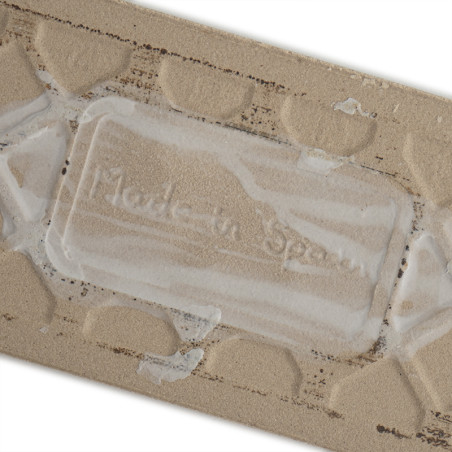 Die beige Keramikfliese weist ein erhabenes geometrisches Muster auf. Der geprägte Text „Made in Spain“ ist inmitten der Textur 