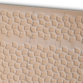 Tan tile features raised, crescent-shaped patterns with slightly uneven texture. Center text reads `MADE IN SPAIN,` indicating i