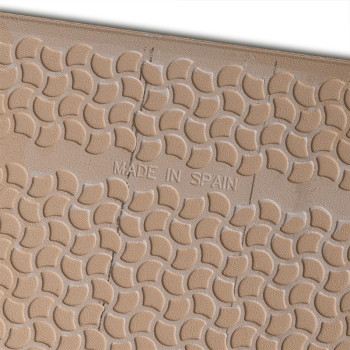 Auf einer hellbraunen Fliese mit einem sich wiederholenden halbkreisförmigen Muster und sichtbaren Rissen steht in der Mitte der