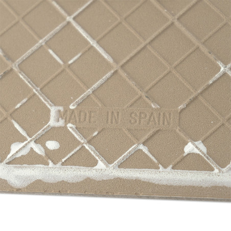 Een beige tegel heeft een gestructureerd rasterpatroon met witte lijnen die elkaar kruisen over het oppervlak. De tekst luidt: `