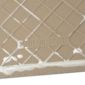 Azulejo cerâmico bege com padrão de grade com resíduo branco, exibindo o texto `MADE IN SPAIN` em relevo.