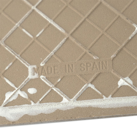 Azulejo cerâmico bege com padrão de grade com resíduo branco, exibindo o texto `MADE IN SPAIN` em relevo. Azulejo cerâmico bege com padrão de grade com resíduo branco, exibindo o texto `MADE IN SPAIN` em relevo.