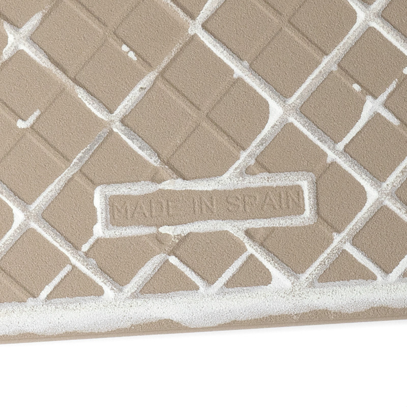 A tan tile features a raised diamond grid pattern filled with white grout. The text `MADE IN SPAIN` is embossed centrally.