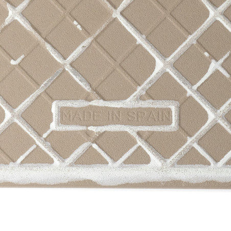 Een getextureerde beige keramische tegel vertoont een geometrisch rasterpatroon. De tekst `MADE IN SPAIN` is in reliëf aangebrac Een getextureerde beige keramische tegel vertoont een geometrisch rasterpatroon. De tekst `MADE IN SPAIN` is in reliëf aangebrac