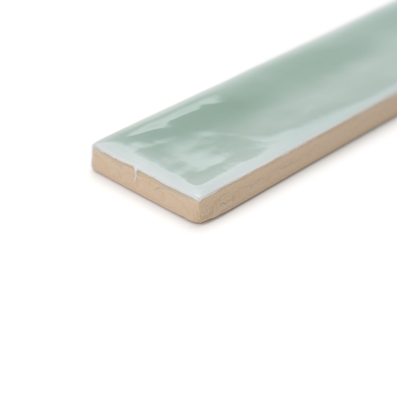 A rectangular tile, glazed with a glossy, light green surface, rests on a plain white background, displaying its thin profile.