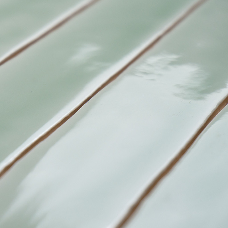 Glossy, rectangular teal tiles aligned in parallel. reflecting light, creating a smooth, clean surface with subtle color variati
